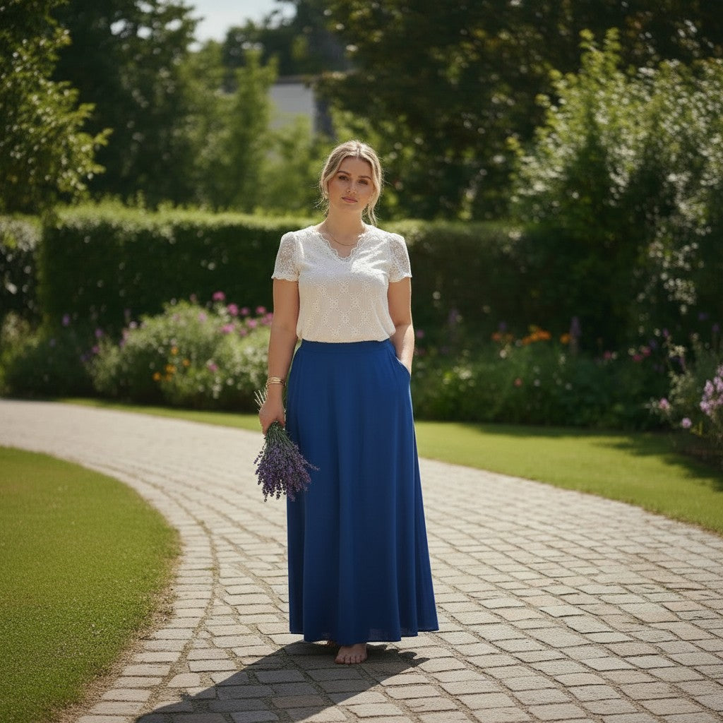 Femme portant une jupe longue fluide bleue La Vie Continue avec poches latérales dans un jardin ensoleillé