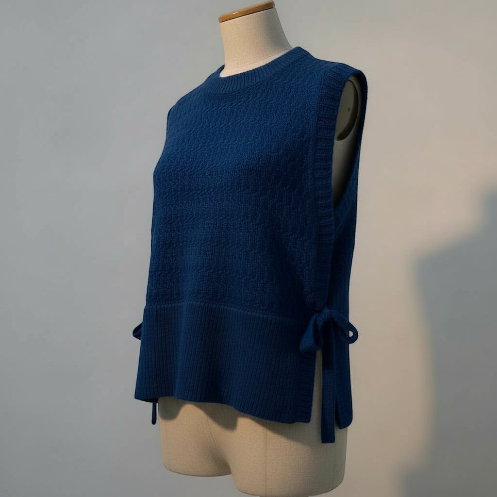 La Vie Continue blue knit vest with crew neck and tie details on the sides. Made from acrylic, polyamide, and polyester blend.