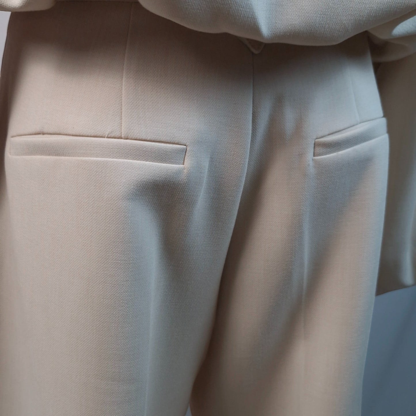 La Vie Continue beige polyester blend trousers with tailored pockets and front pleats.