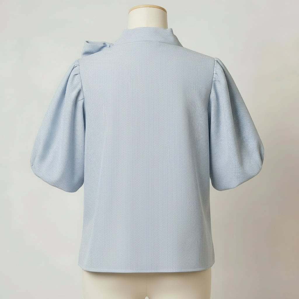 La Vie Continue light blue pinstripe cotton-blend blouse with short puff sleeves and a bow detail at the collar.