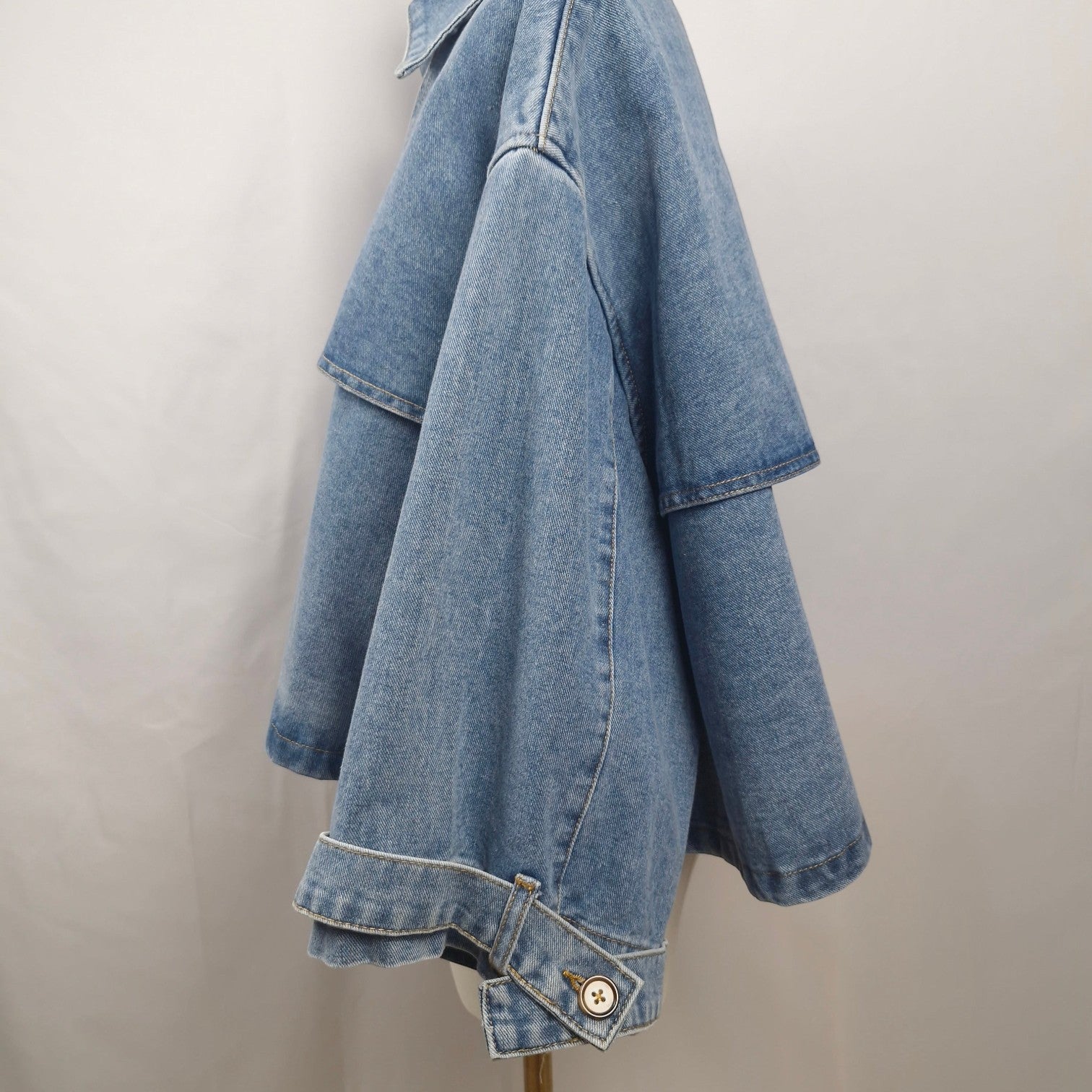 La Vie Continue light wash denim cape jacket with button front and relaxed fit.
