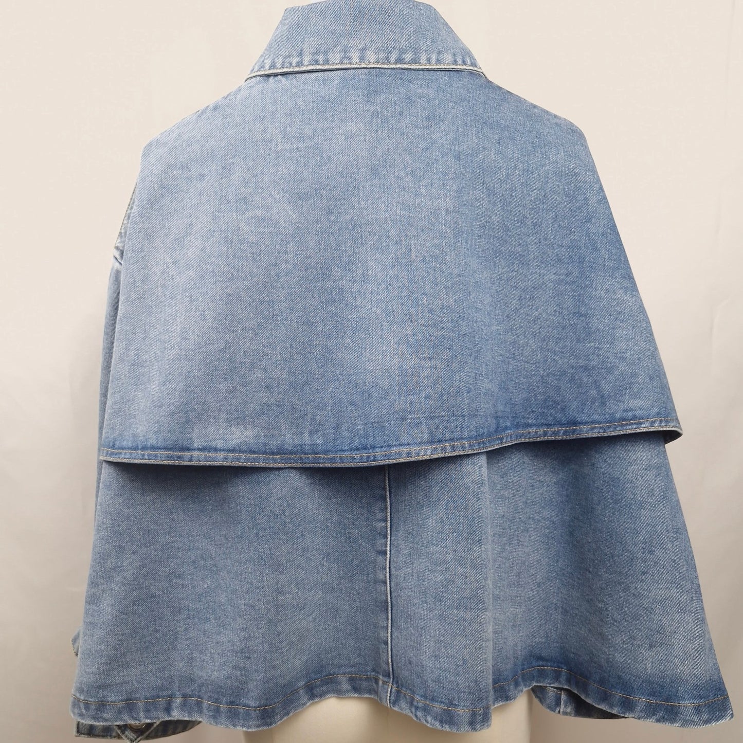 La Vie Continue light wash denim cape jacket with a relaxed fit and button-front closure.