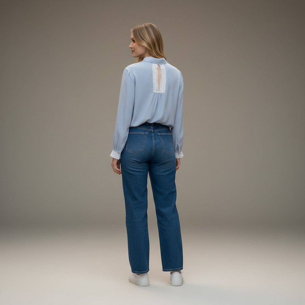 La Vie Continue light blue viscose-Tencel blend blouse with delicate lace trim on the back and cuffs, worn by a model with jeans.
