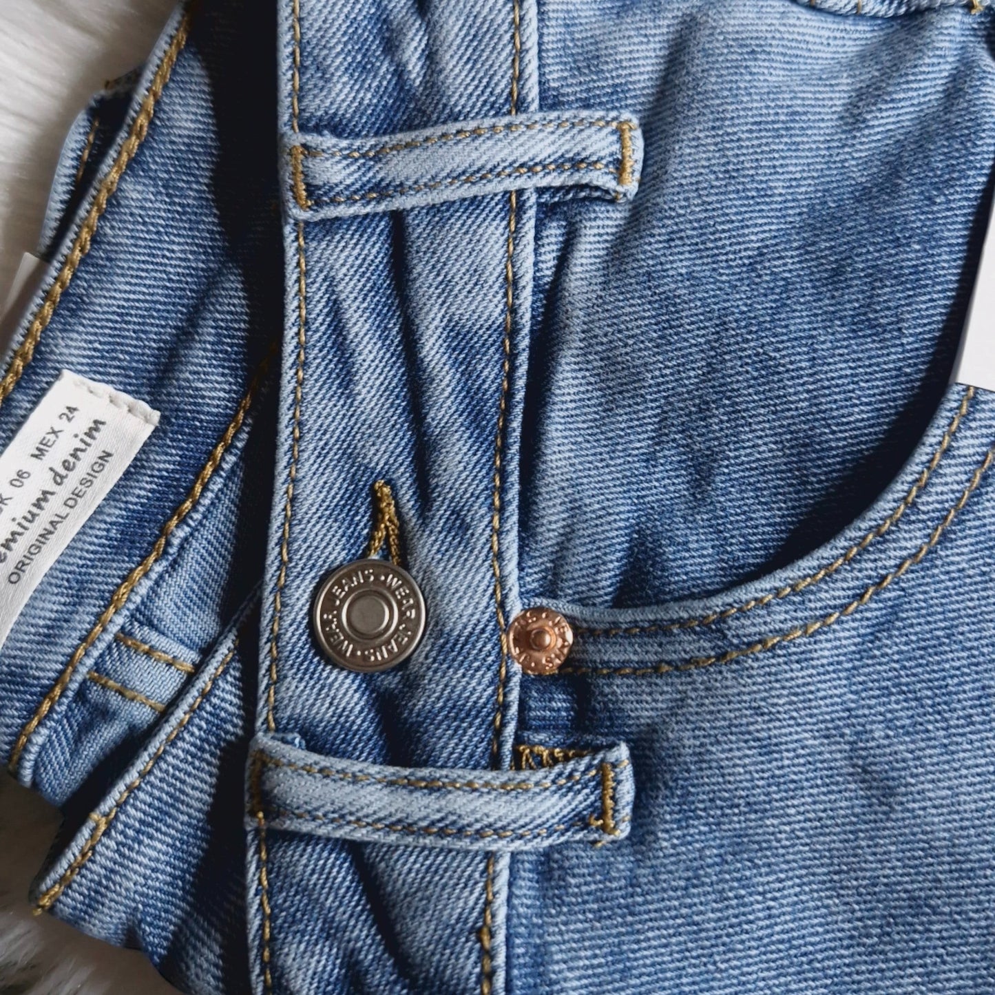 La Vie Continue light blue denim wide leg jeans with asymmetric button detail and gold stitching.