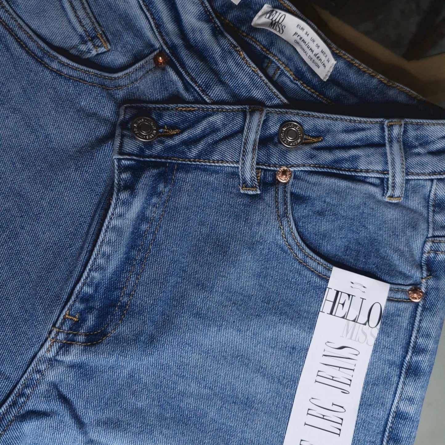 La Vie Continue light blue denim wide leg jeans with asymmetric button detail and copper rivets.