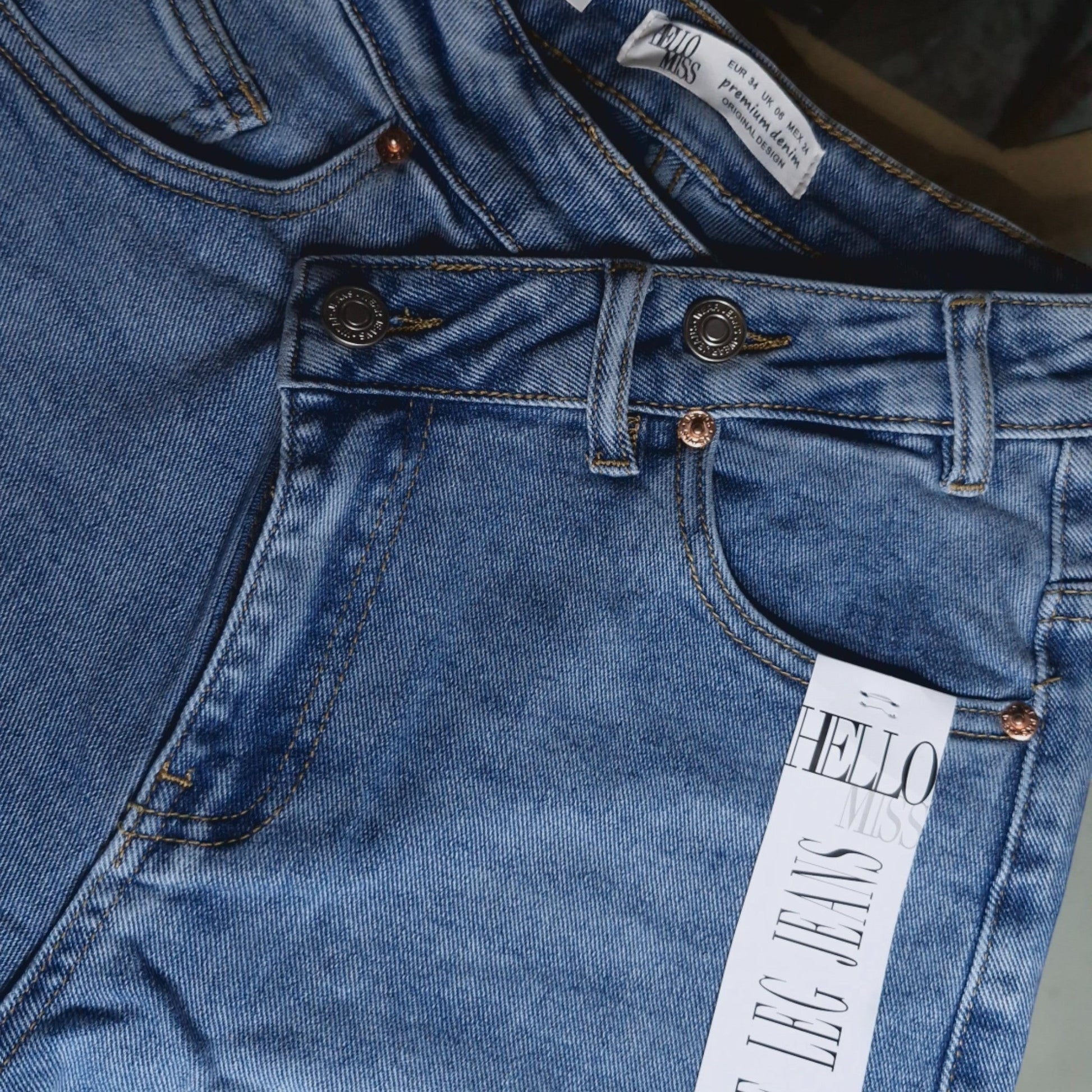 La Vie Continue light blue denim wide leg jeans with asymmetric button detail and copper rivets.