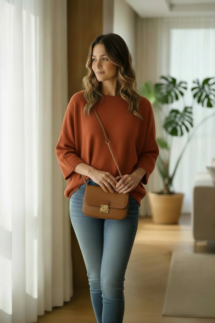 La Vie Continue rust-coloured wide-sleeve knit sweater on a woman wearing blue jeans and a tan crossbody bag.